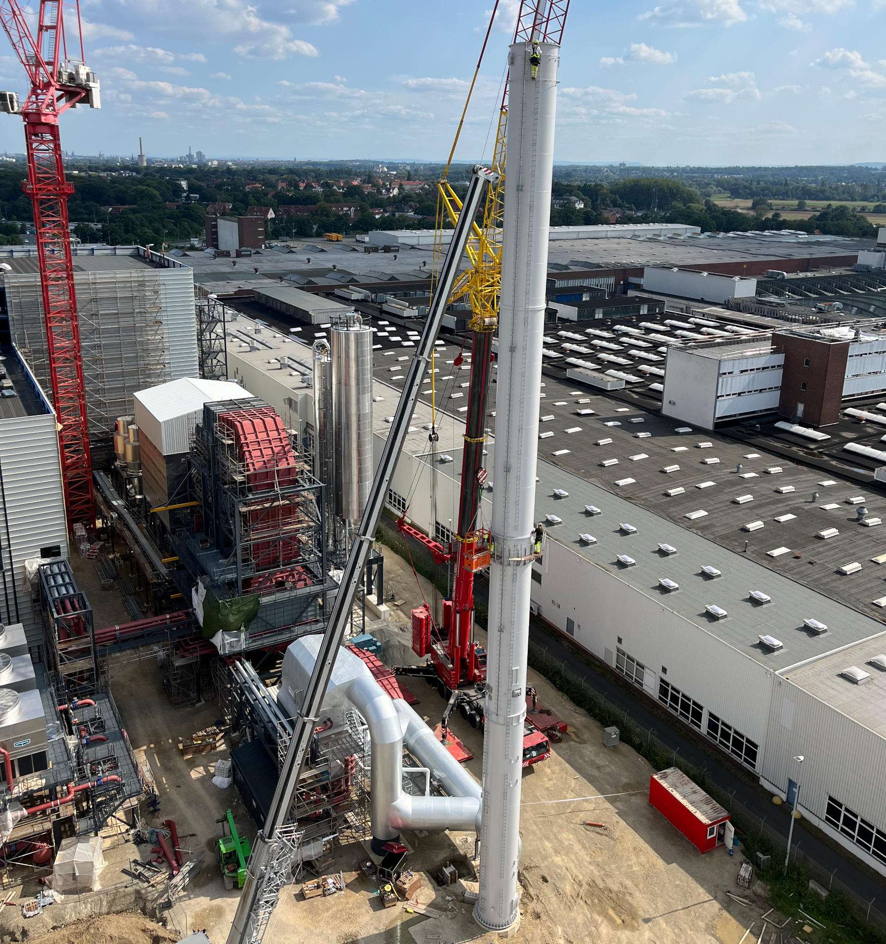 Höhenarbeit an einer Industrieanlage, im Hintergrund Kran und Gewerbeflächen